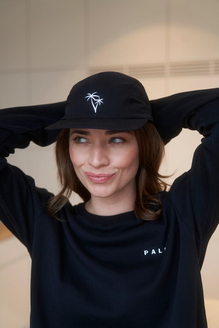 Girl wearing a black 5 panel cap with palm print